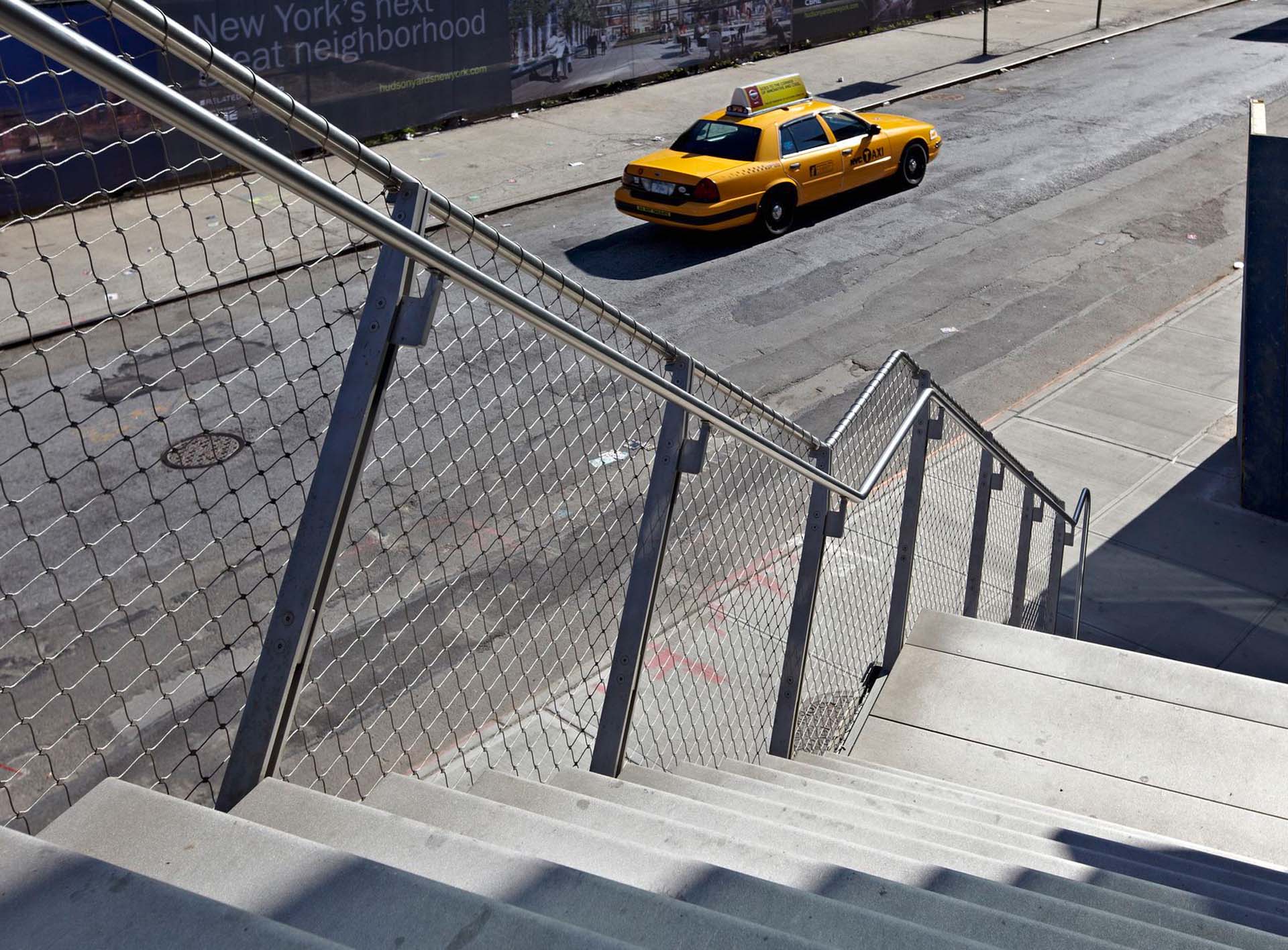 A yellow New York cab in front of a stair with a Webnet railing